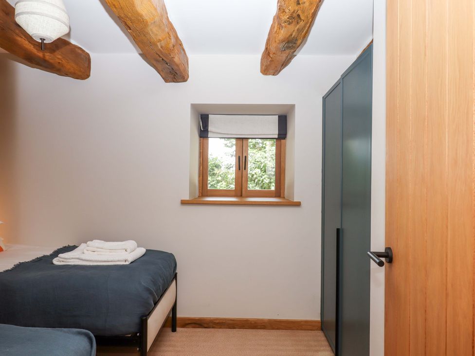 A bedroom with two beds and a window at Lower Walreddon Barn Tavistock