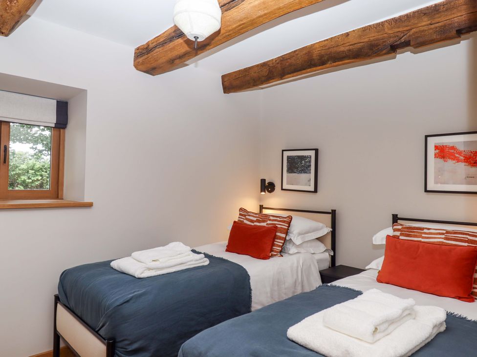 A bedroom with two beds and window at Lower Walreddon Barn Tavistock