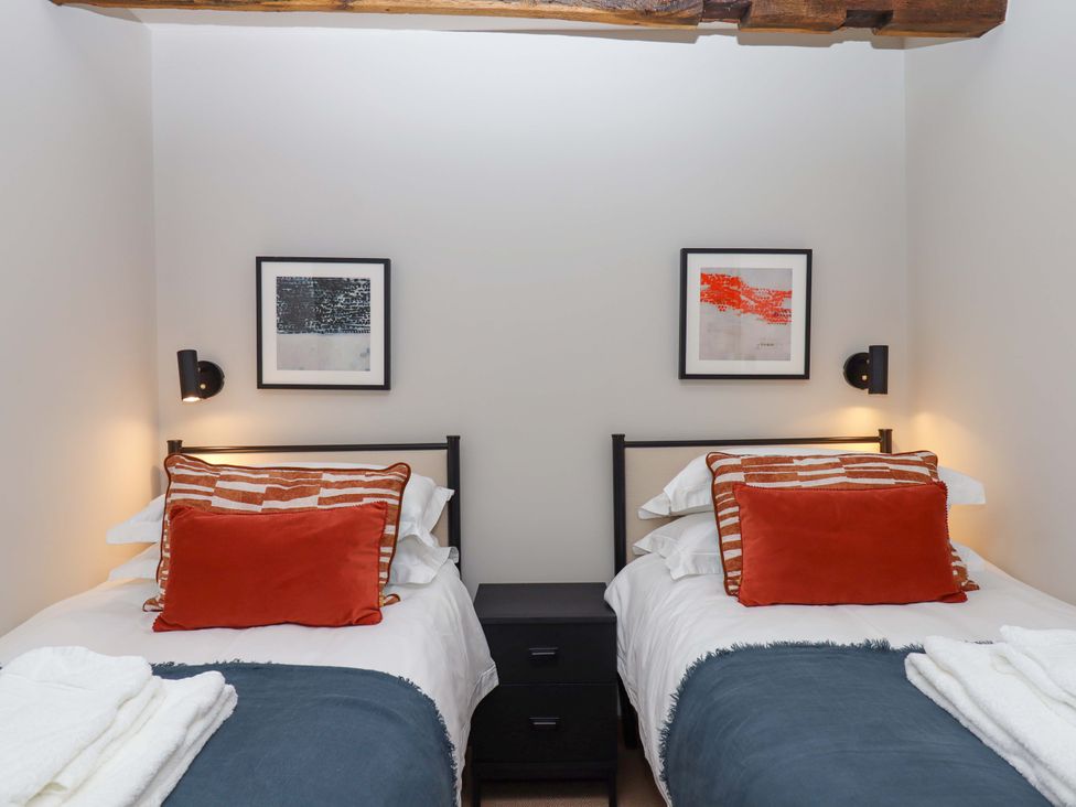 A bedroom with two beds and artwork on the wall at Lower Walreddon Barn in Tavistock