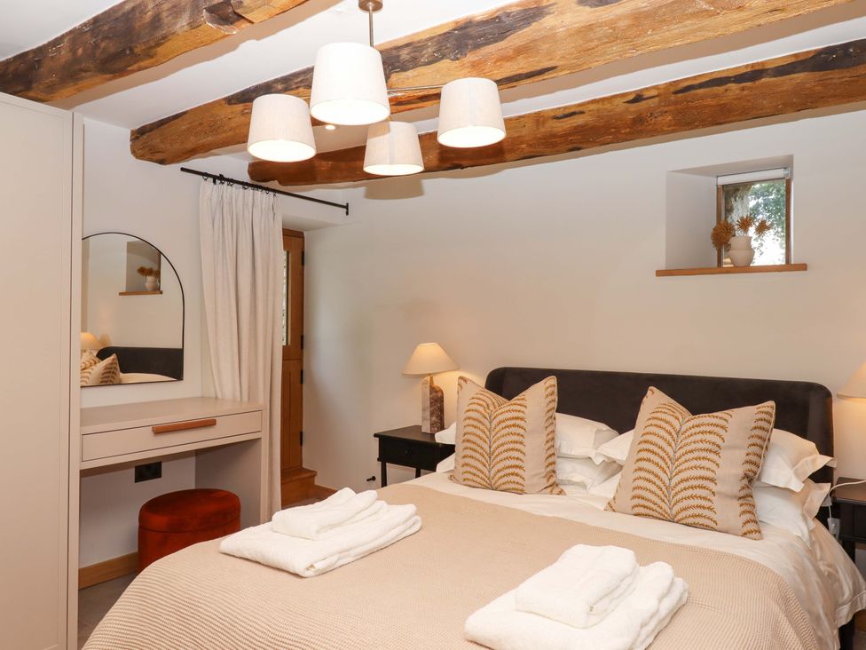 A bedroom with a bed and a dressing table at Lower Walreddon Barn in Tavistock