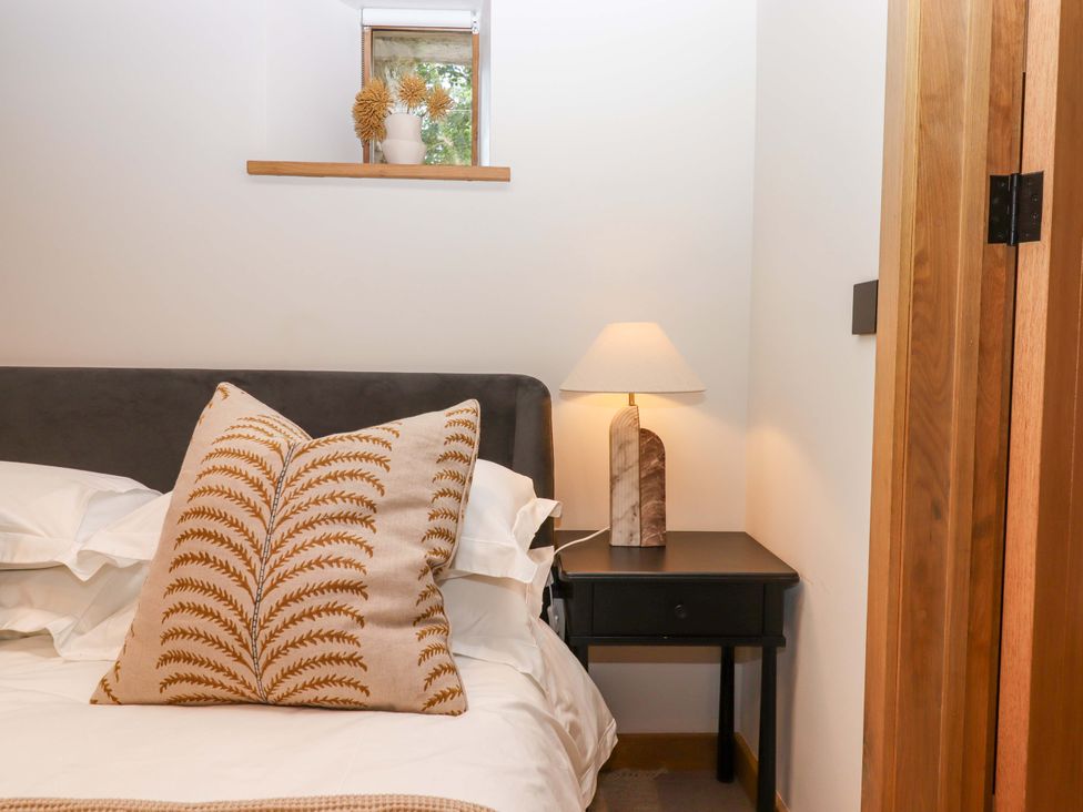 A bedroom with a bed and lamp on a nightstand at Lower Walreddon Barn Tavistock