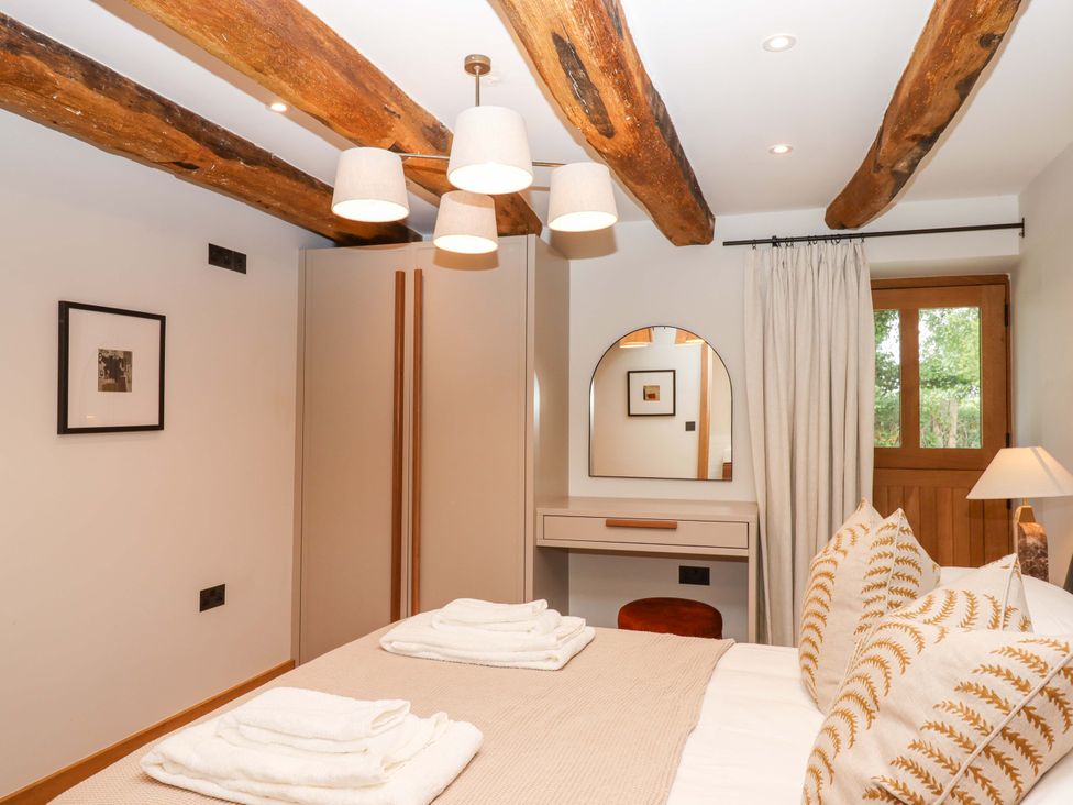 A bedroom with a bed and wardrobe at Lower Walreddon Barn in Tavistock