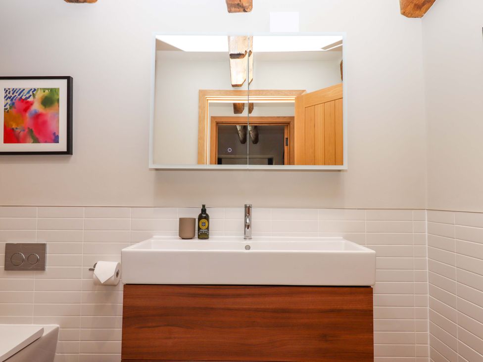 A bathroom with a sink and mirror at Lower Walreddon Barn in Tavistock