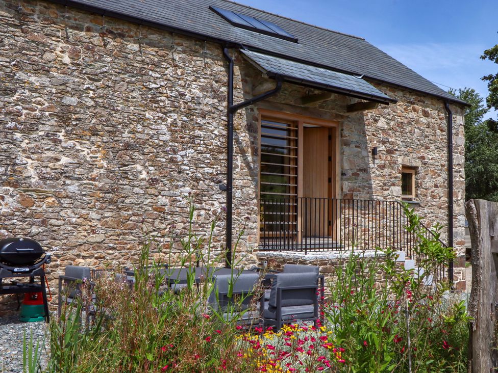 An outdoor area with stone wall and seating at Lower Walreddon Barn Tavistock