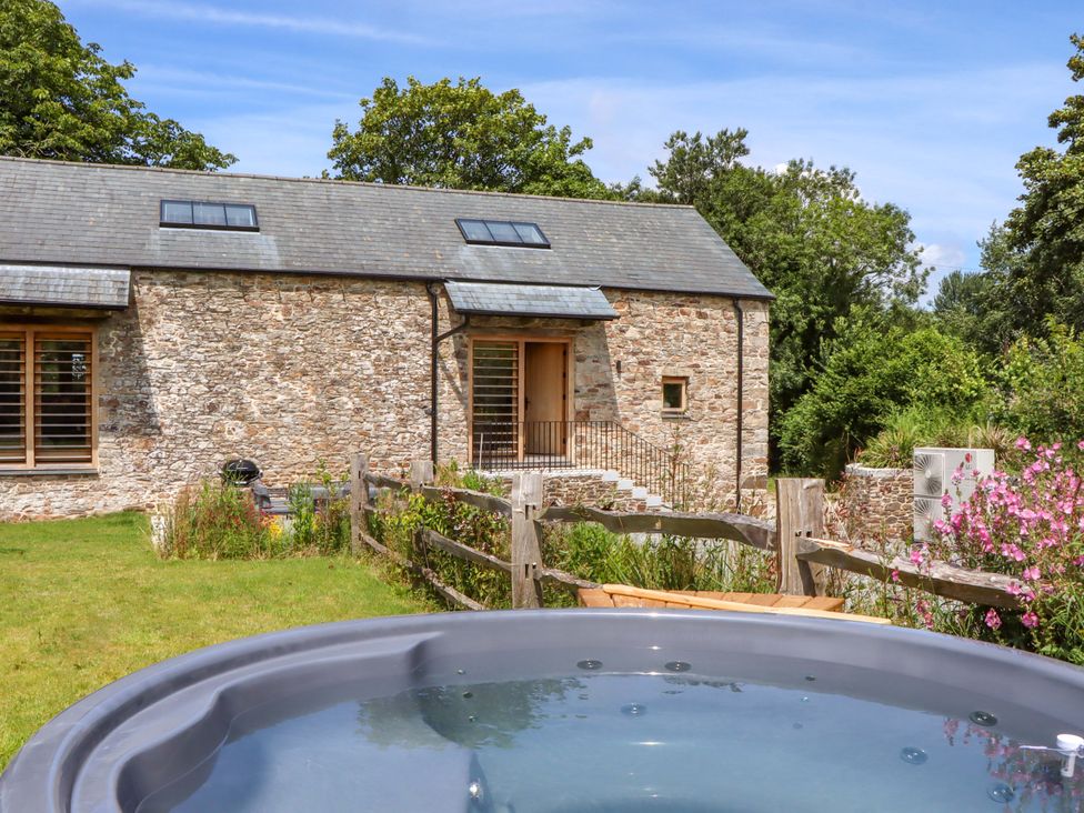 An outdoor view of a barn with a hot tub and garden at Lower Walreddon Barn in Tavistock