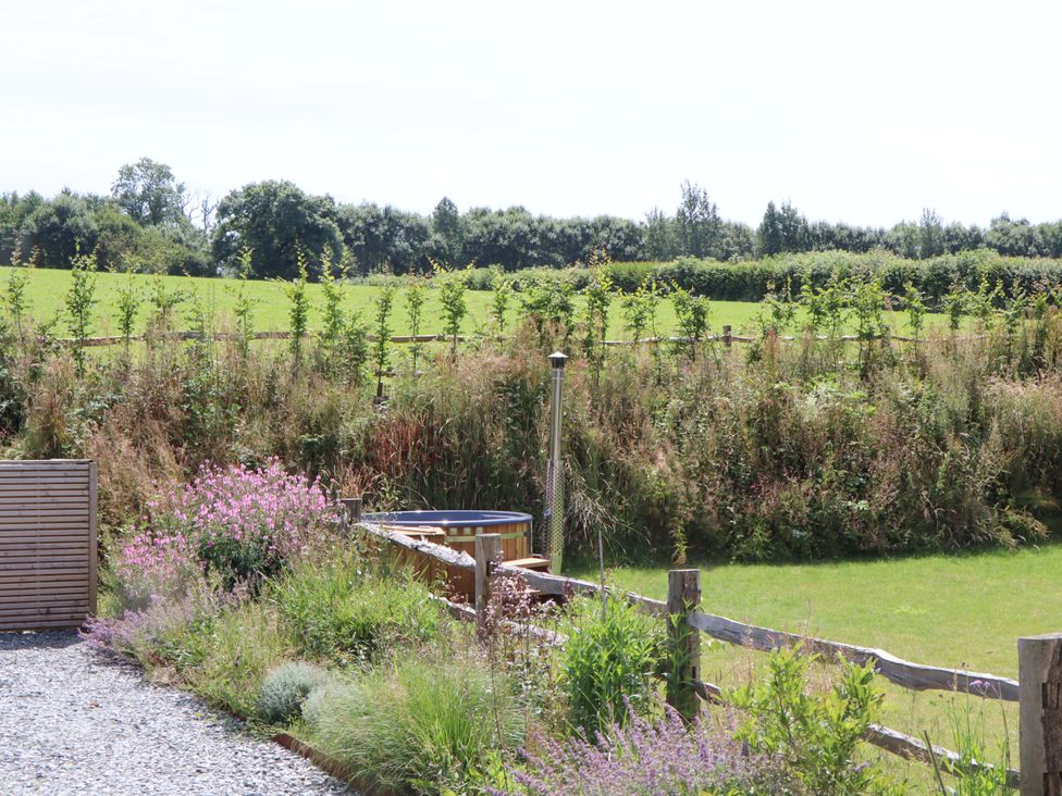 A garden with flowers and a hot tub at Lower Walreddon Barn Tavistock