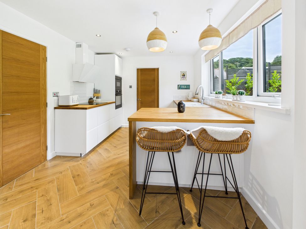 A kitchen with a counter and bar stools at 59a Gwscwm Road