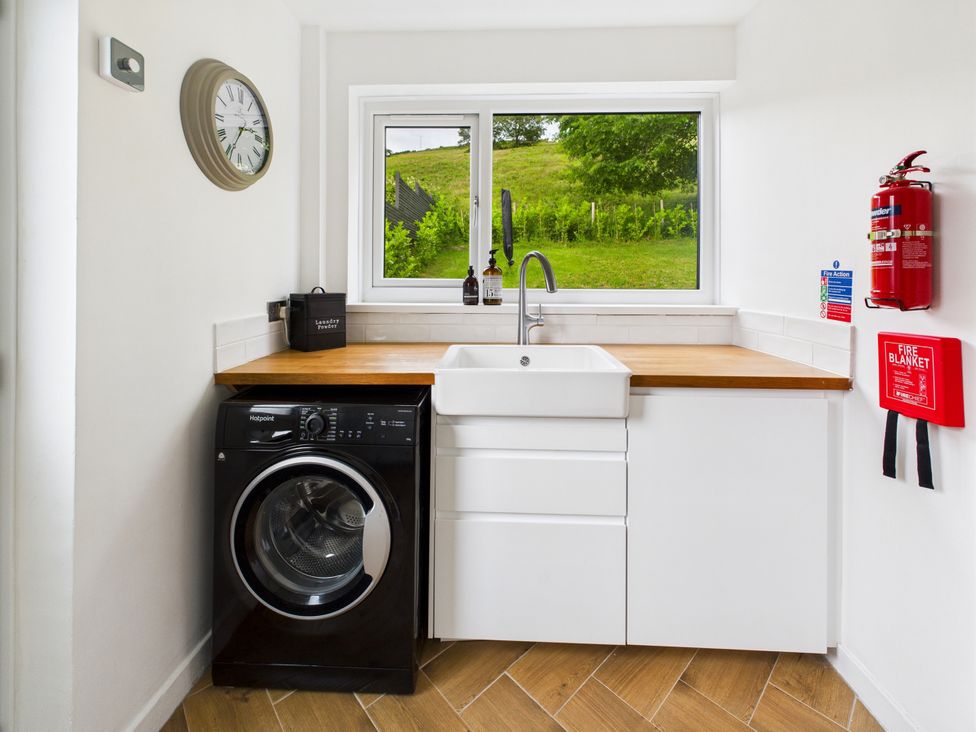 A laundry room with a washing machine and a sink at 59a Gwscwm Road