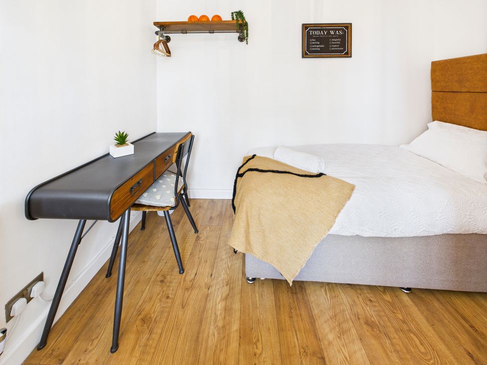 A bedroom with a bed, desk, and shelf at 59a Gwscwm Road