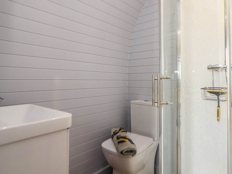 A bathroom with a toilet, shower and towel at Honeypot Hideaways - Manuka