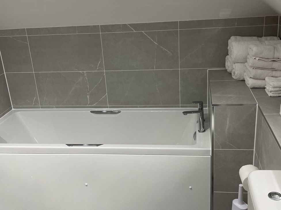 A bathroom with a bathtub and stacked towels at The ClockTower in Perth
