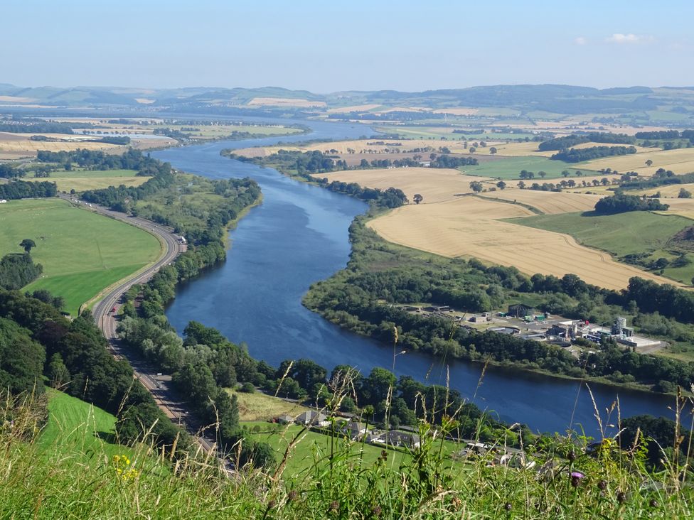 A river surrounded by fields and trees at The ClockTower in Perth