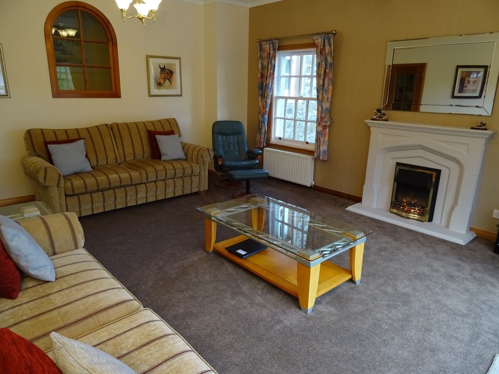 A living room with a sofa, chair, coffee table, and fireplace at Coach House 4 in Perth