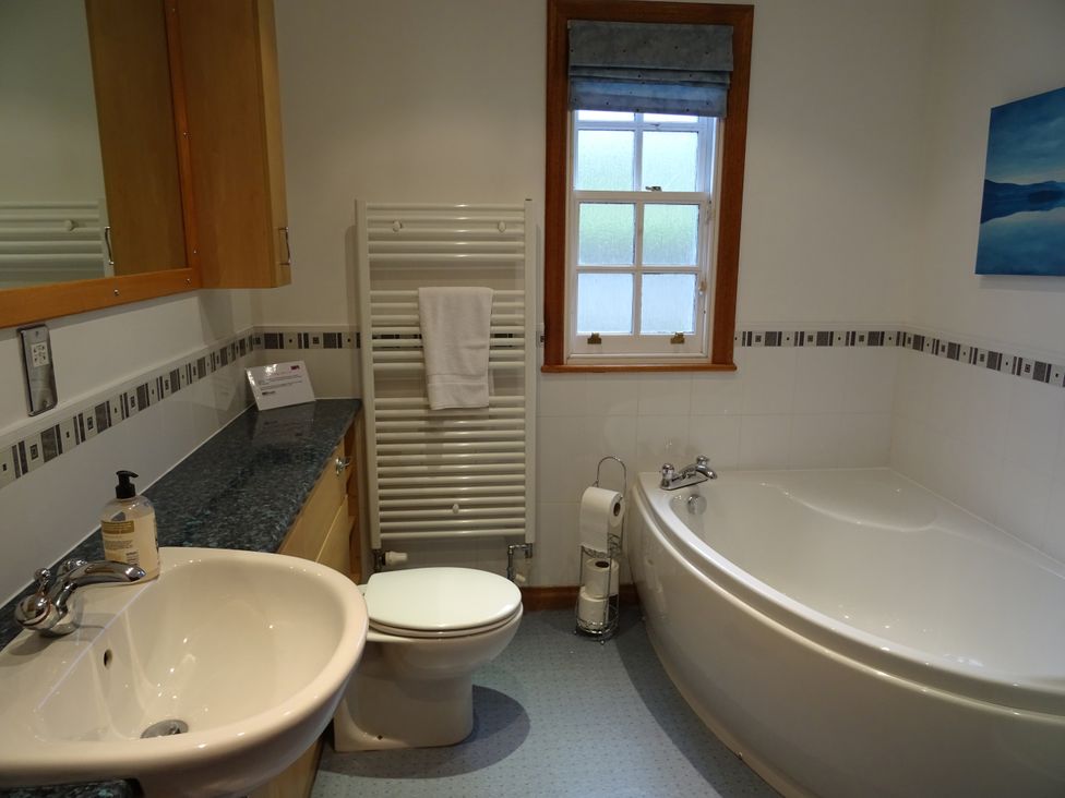 A bathroom with a bath tub, sink, and toilet at Coach House 4, Perth