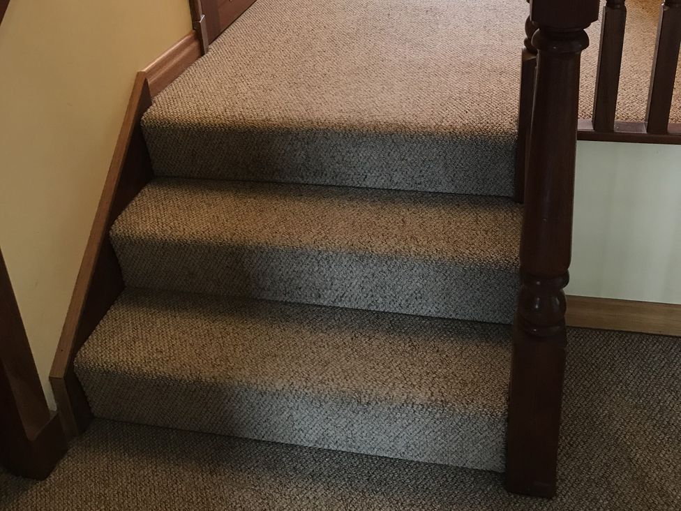 A staircase with carpet and a wooden railing at Coach House 5, Perth