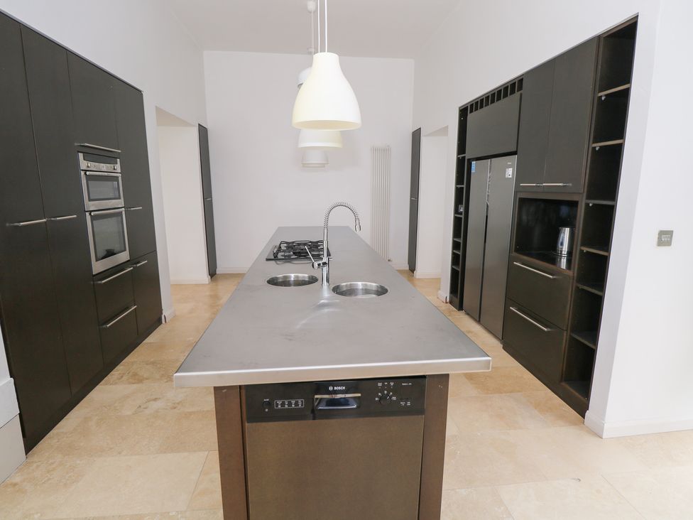 A kitchen with a central island featuring a stove and sink at The Cottage in Ballinagleira