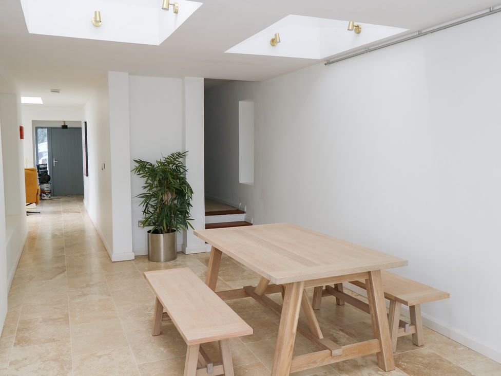 A dining room with a wooden table and benches at The Cottage in Ballinagleira