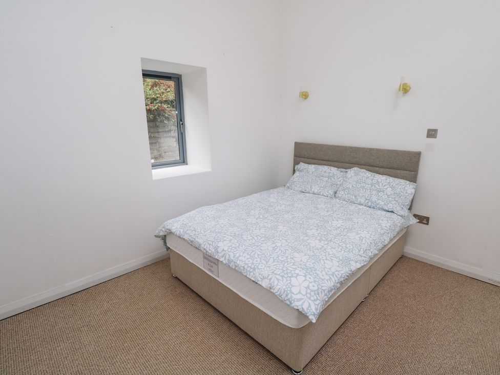 A bedroom with a bed and window at The Cottage in Ballinagleira
