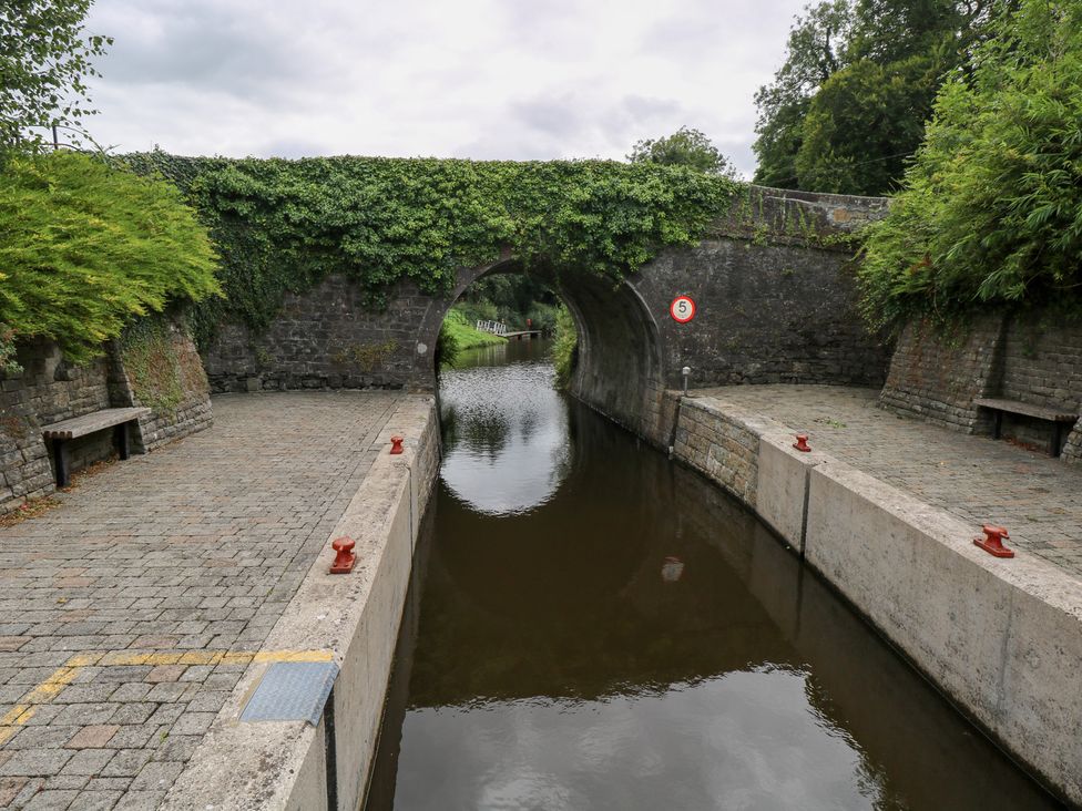 A canal with a stone bridge and benches at The Cottage in Ballinagleira