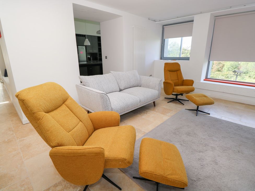 A living room with a sofa and chairs at The Cottage in Ballinagleira