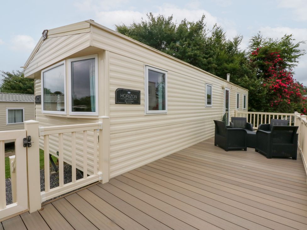 A mobile home with a deck and chairs at Mountain View in Pwllheli