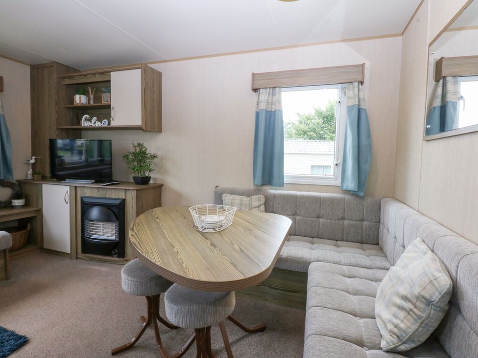 A living room with a table and seating area at Mountain View in Pwllheli