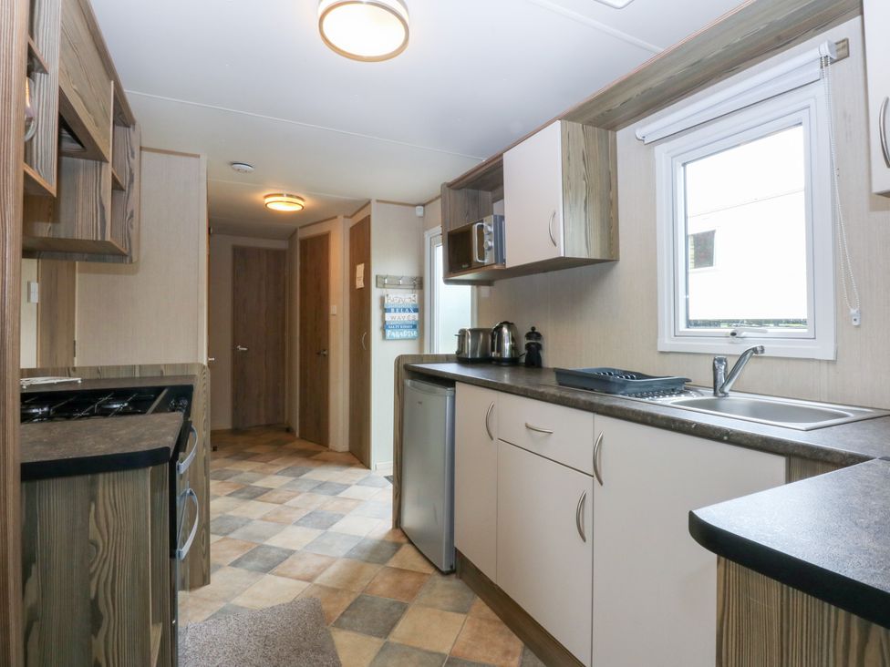 A kitchen with appliances and cabinets at Mountain View in Pwllheli