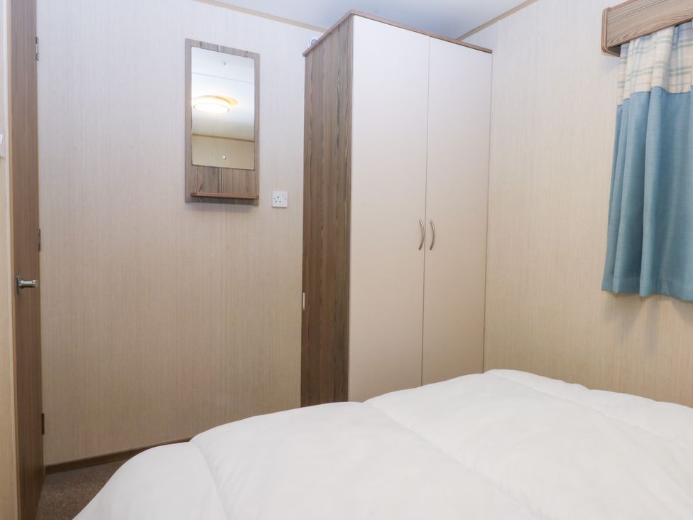 A bedroom with a wardrobe and a mirror at Mountain View in Pwllheli