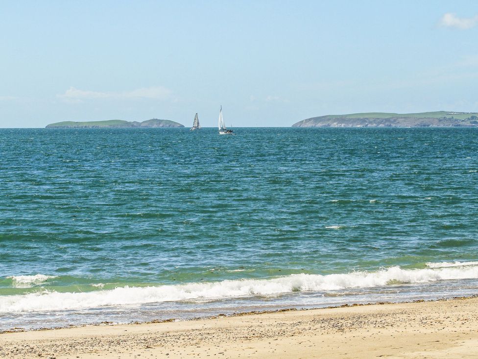 A beach with sailboats and islands in the background at Mountain View Haven/Hafan Y Mor near Pwllheli