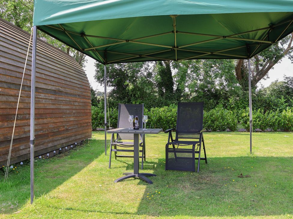 A garden area with a table and chairs under a gazebo at Honeypot Hideaways - Clover