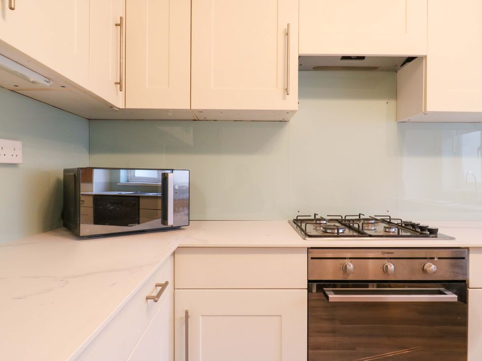 A kitchen with a microwave and gas stove at 13A Westgate Terrace in Whitstable