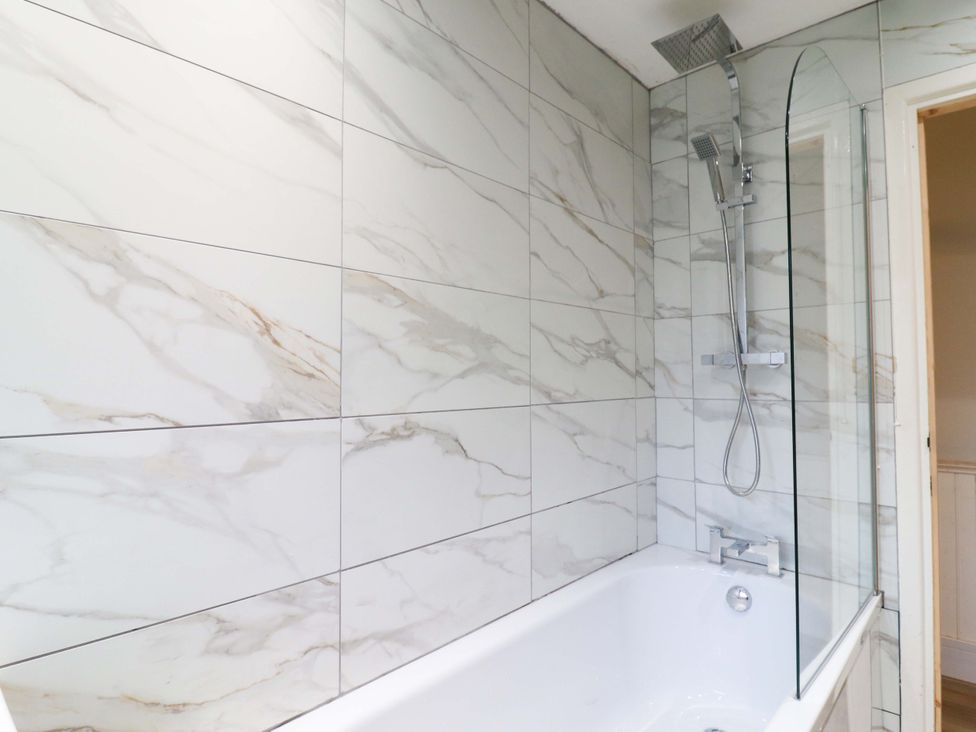 A bathtub with a showerhead and glass screen at 13A Westgate Terrace in Whitstable
