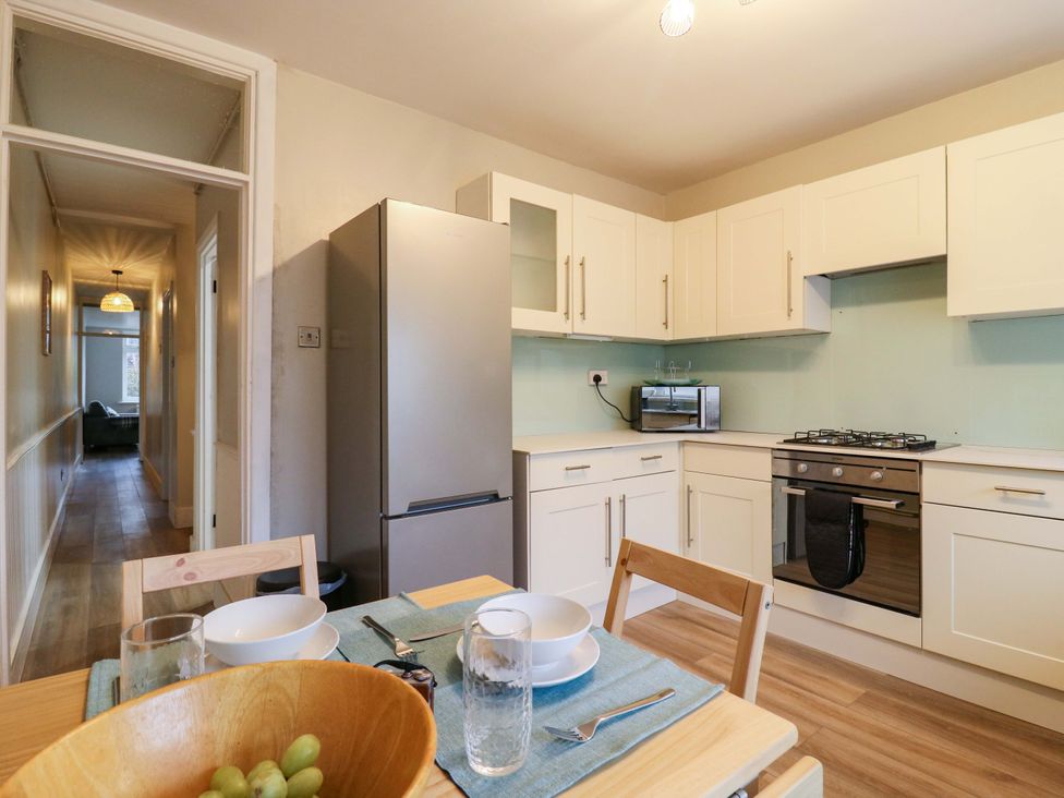 A kitchen with refrigerator, stove, and dining table at High Tide in Whitstable