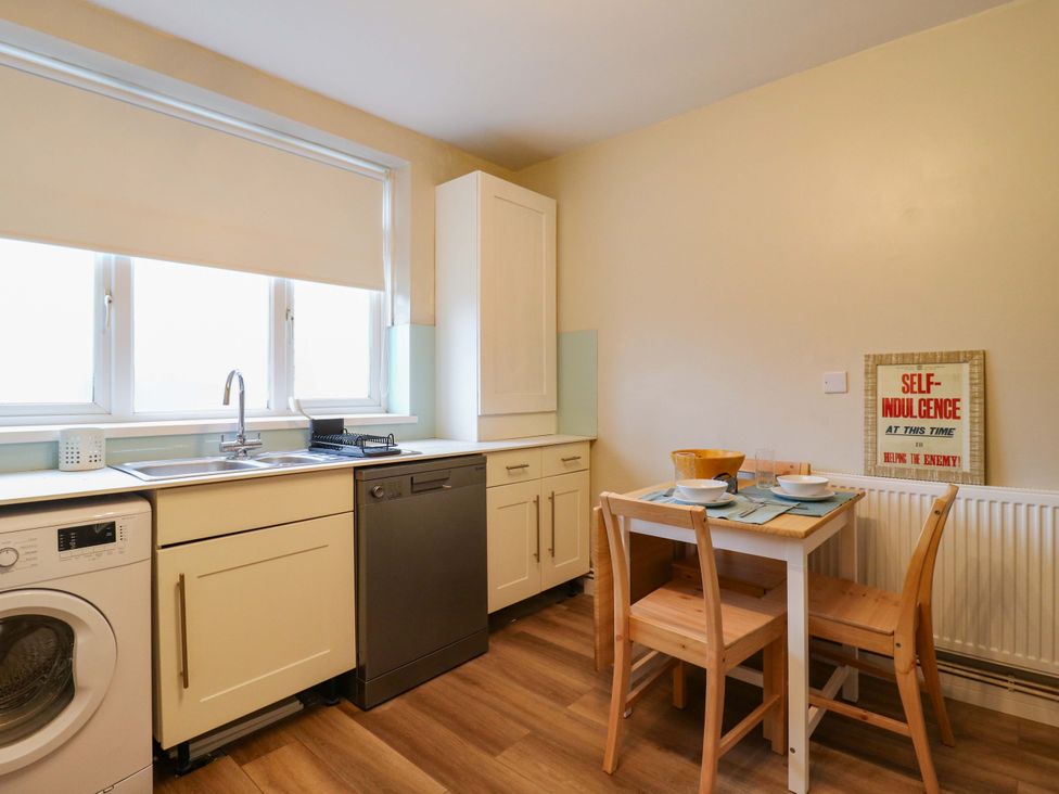 A kitchen with a washing machine and a dining table at High Tide in Whitstable