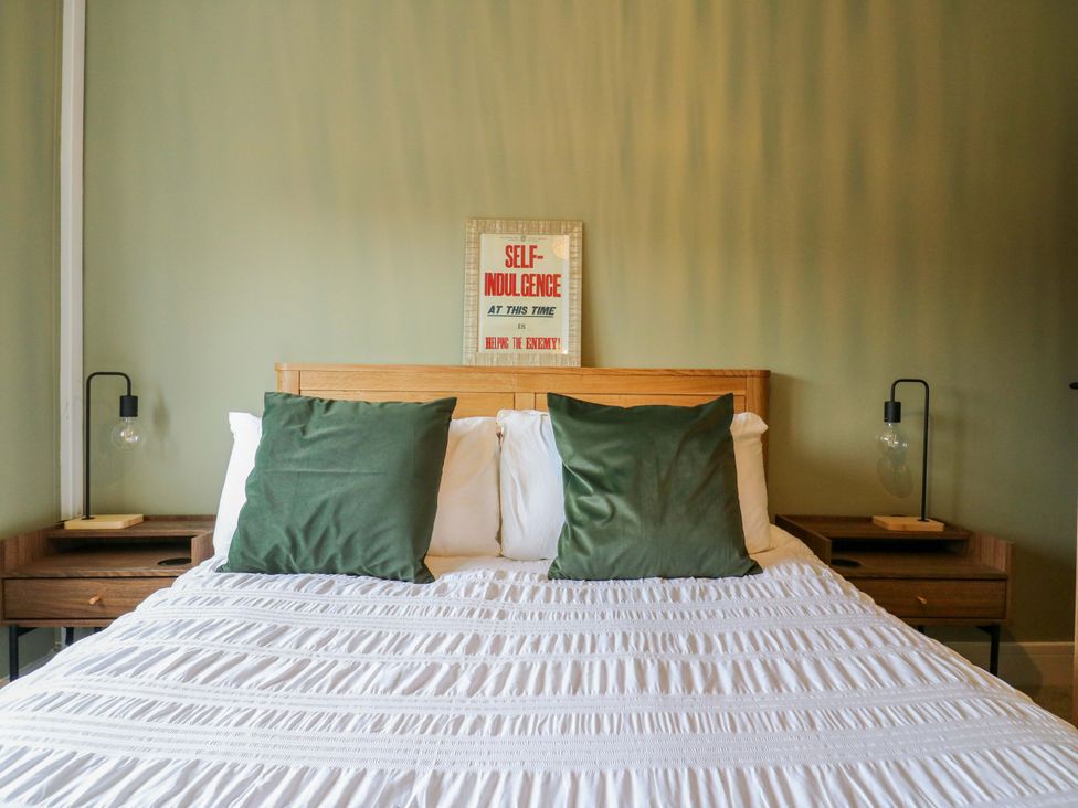 A bedroom with a bed, pillows, and wall art at High Tide in Whitstable