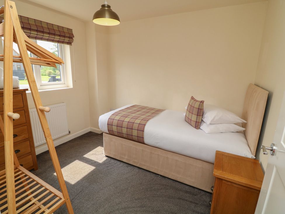 A bedroom with a single bed and wooden furniture at Lodge 8 in Brigg