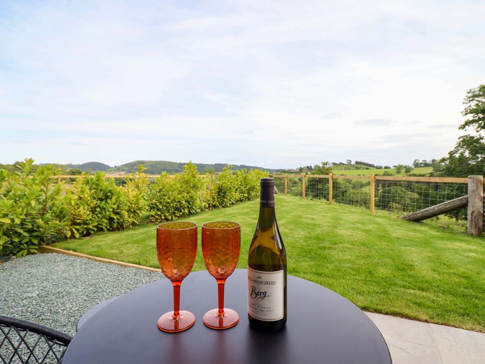 A table with wine glasses and a bottle overlooking the garden at Charollais in Oswestry