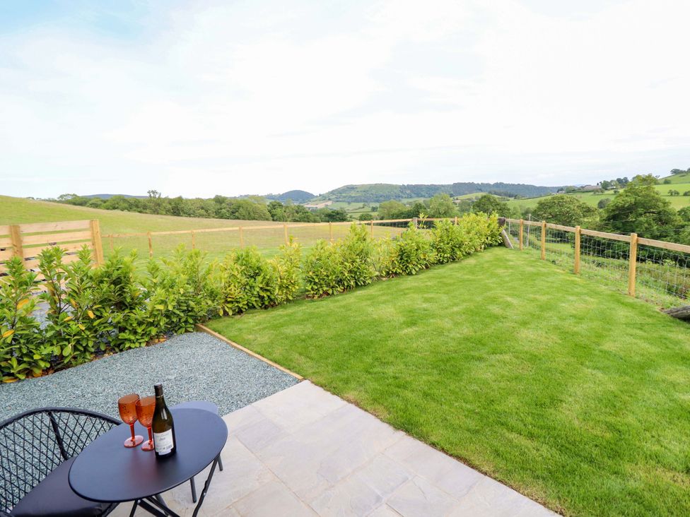 An outdoor area with a table and chairs overlooking the landscape at Charollais in Oswestry