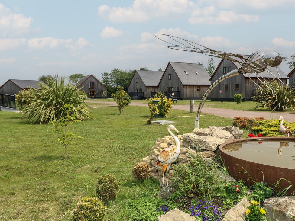 An outdoor area with wooden cabins and a water feature at Lodge 13, Brigg