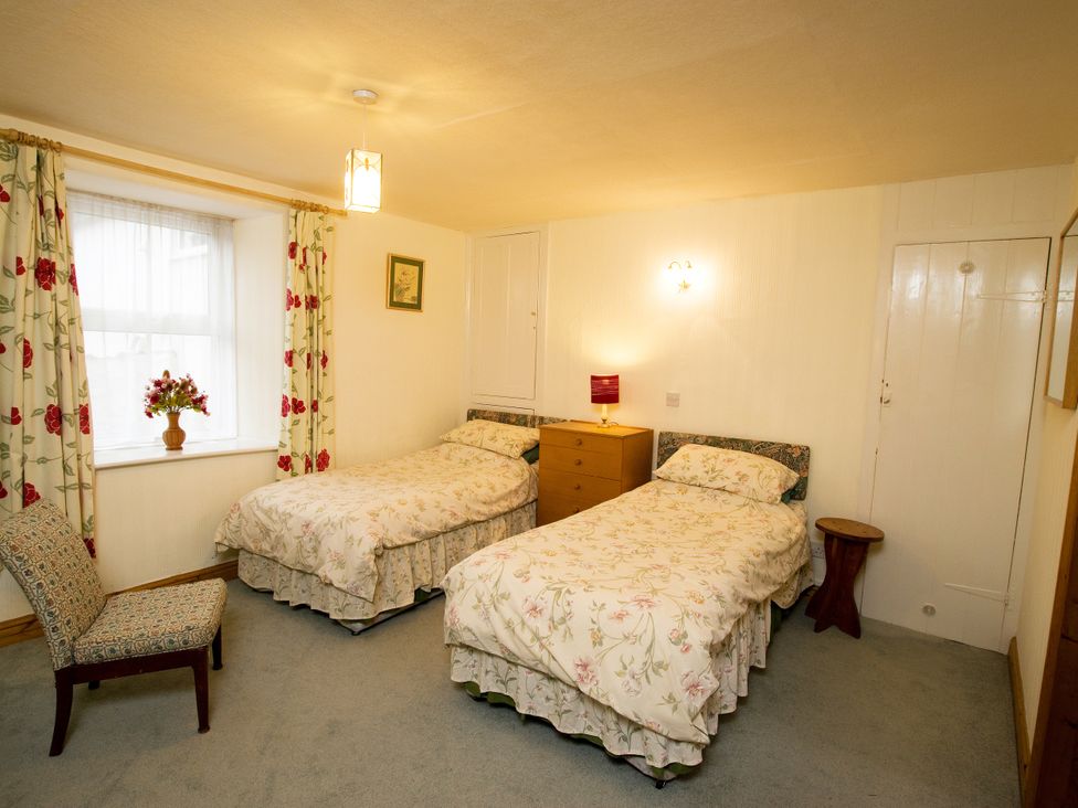 A bedroom with two beds and a chair at Chyandaunce in Gulval