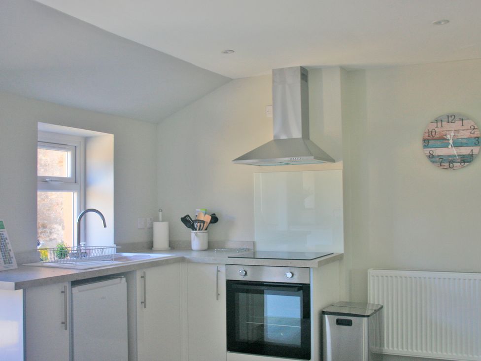 A kitchen with sink, cooker, and window at 2 Links Place in Nairn