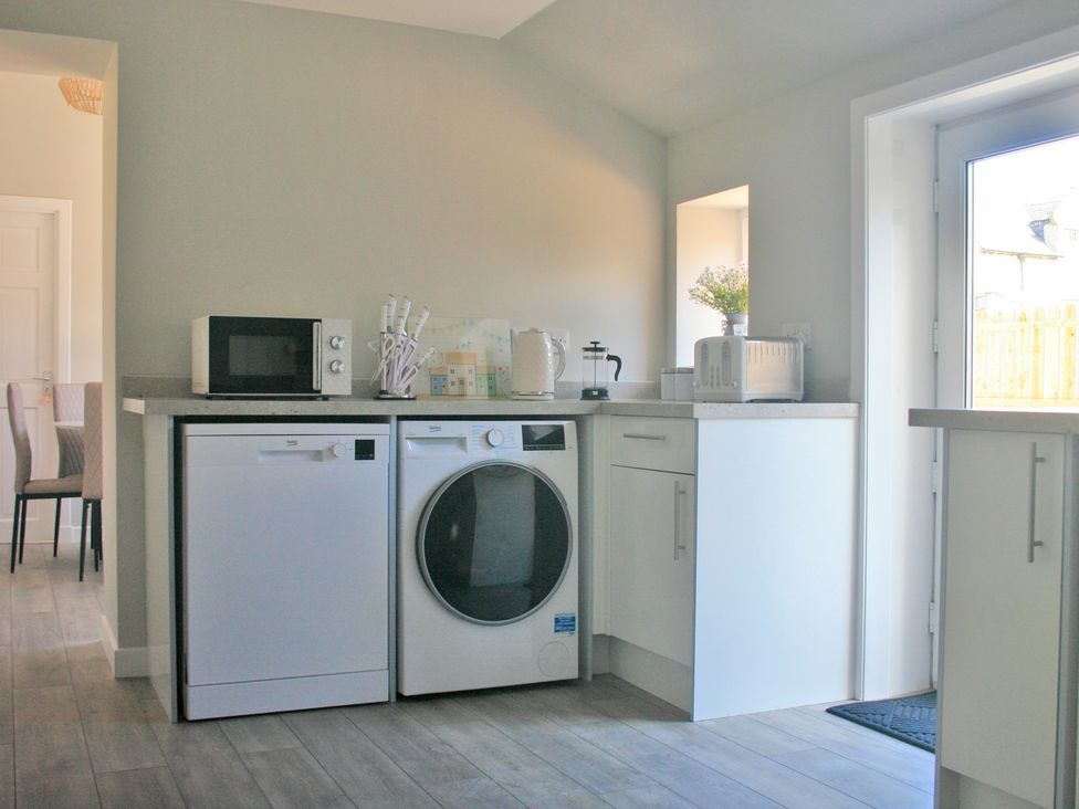 A kitchen with appliances including a microwave and washing machine at 2 Links Place Nairn