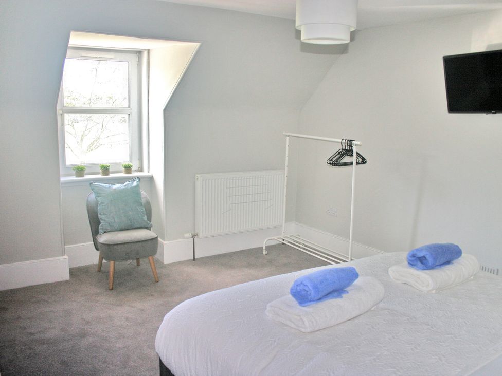 A bedroom with a bed and a chair at 2 Links Place Nairn