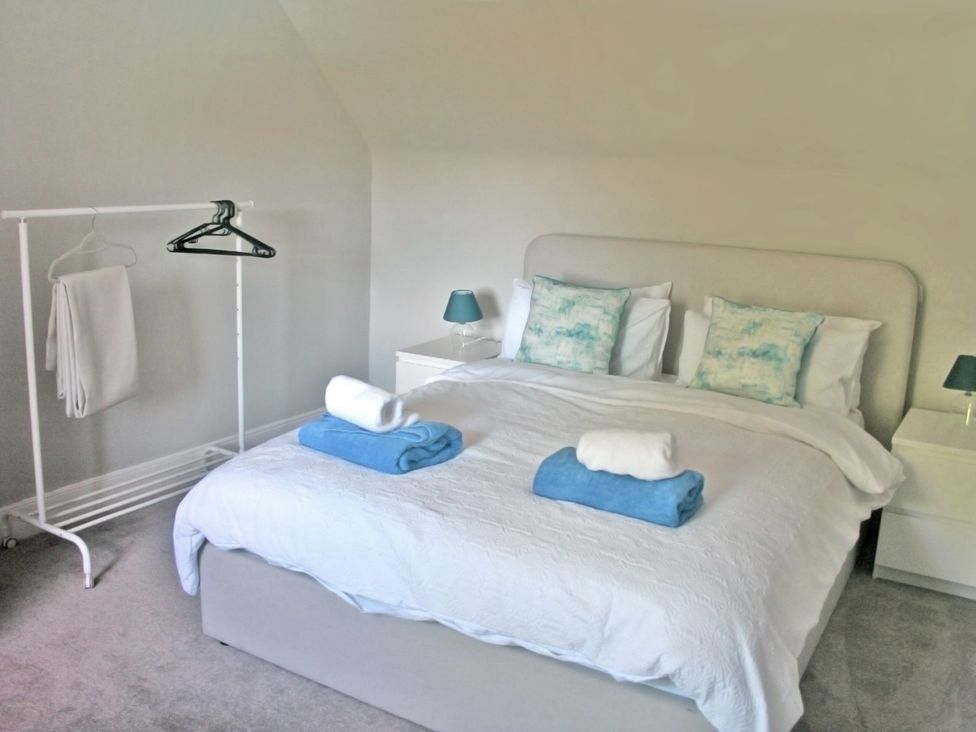 A bedroom with a bed, towels, and a clothes rack at 2 Links Place Nairn