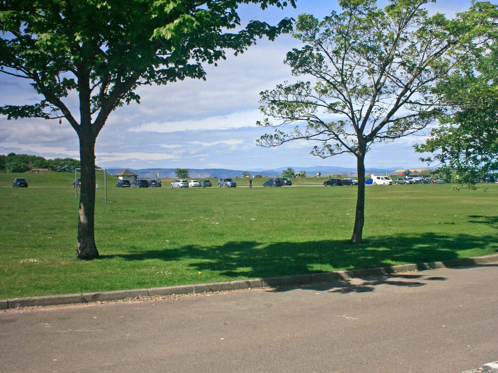 A view of trees and parked cars on grass at 2 Links Place in Nairn