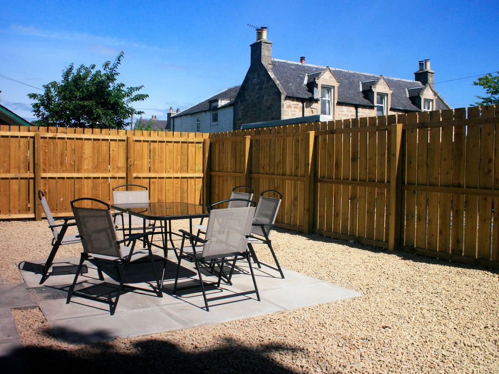 An outdoor area with a table and chairs at 2 Links Place in Nairn