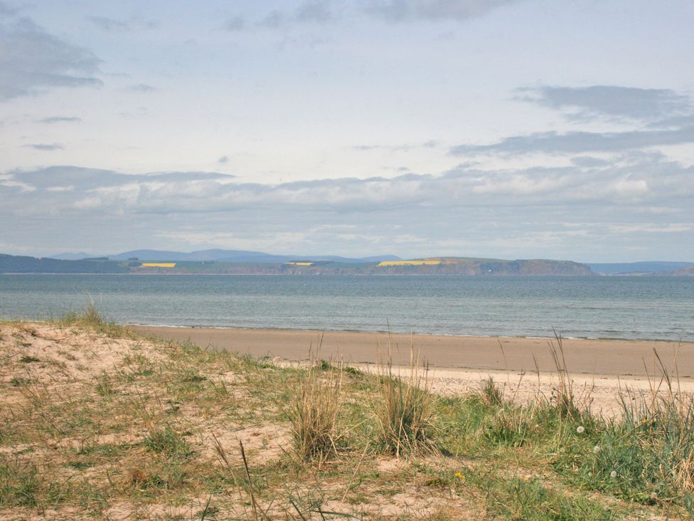 A coastal scene with sand and grass near the shore at 2 Links Place Nairn