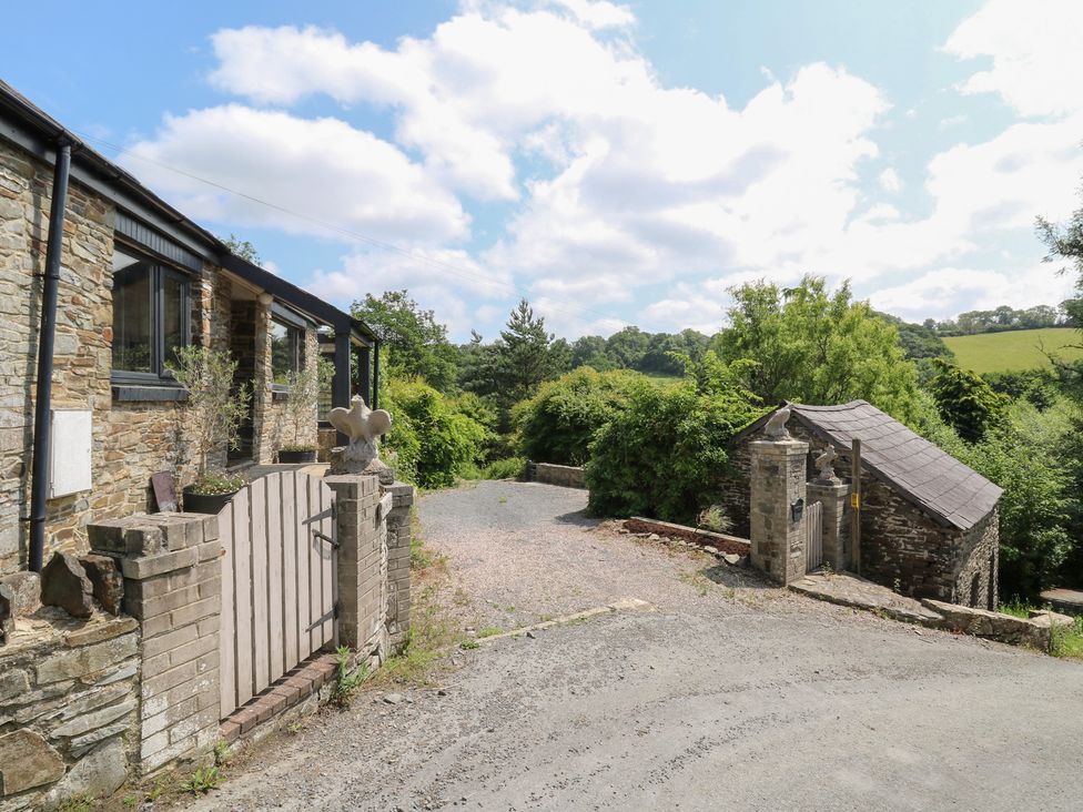 An outdoor area with a stone house and gravel driveway at The Old Barn in Ciliau Aeron near Aberaeron