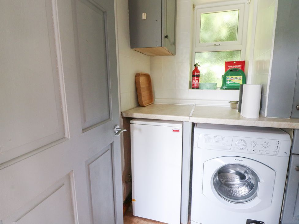 A laundry room with a washing machine and fridge at The Old Barn in Ciliau Aeron near Aberaeron