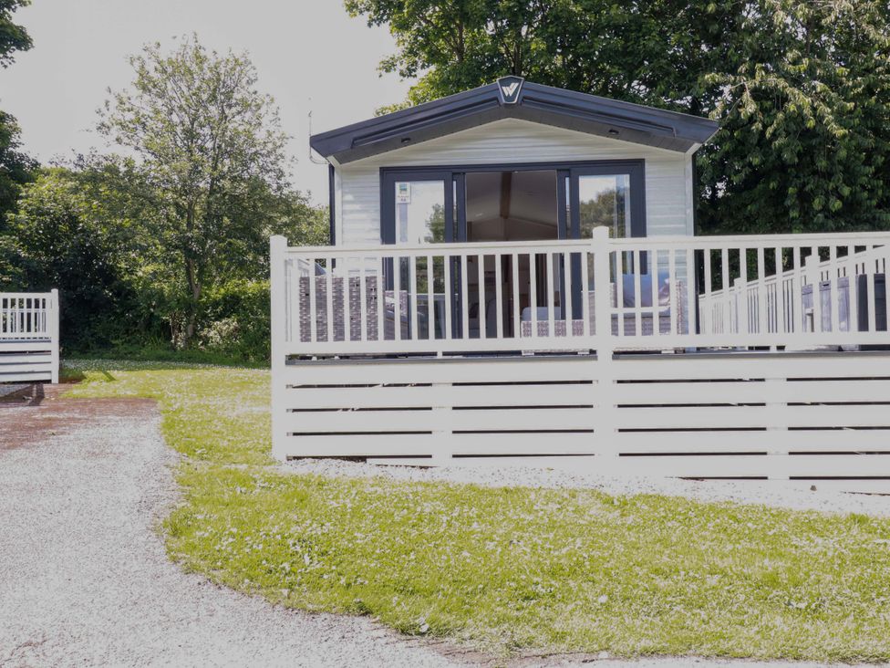 A mobile home with decking and grass area at Meadow 46 in Newquay